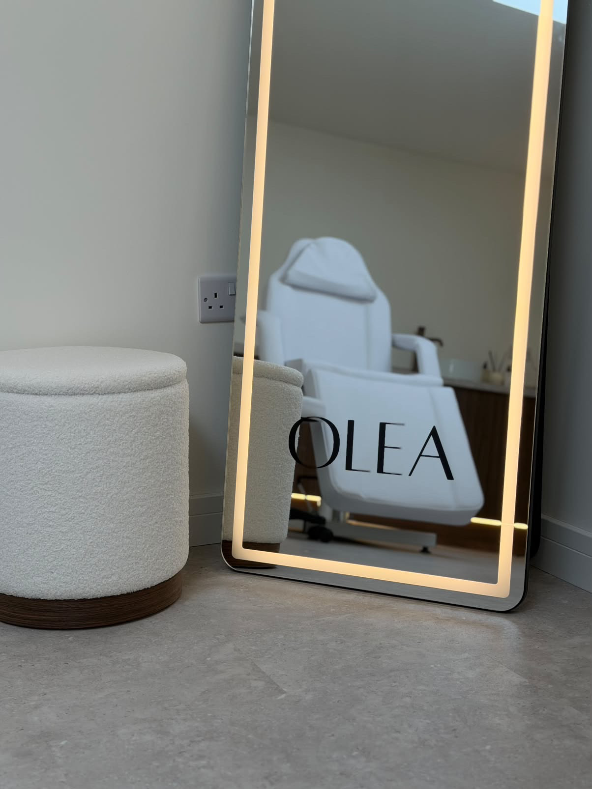 Illuminated OLÉA mirror reflecting a white treatment chair