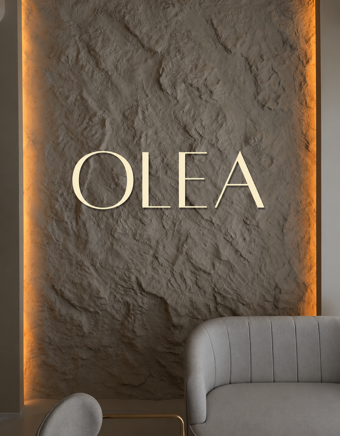 The OLÉA wordmark in cream lettering on a warmly lit textured stone wall above curved cream seating